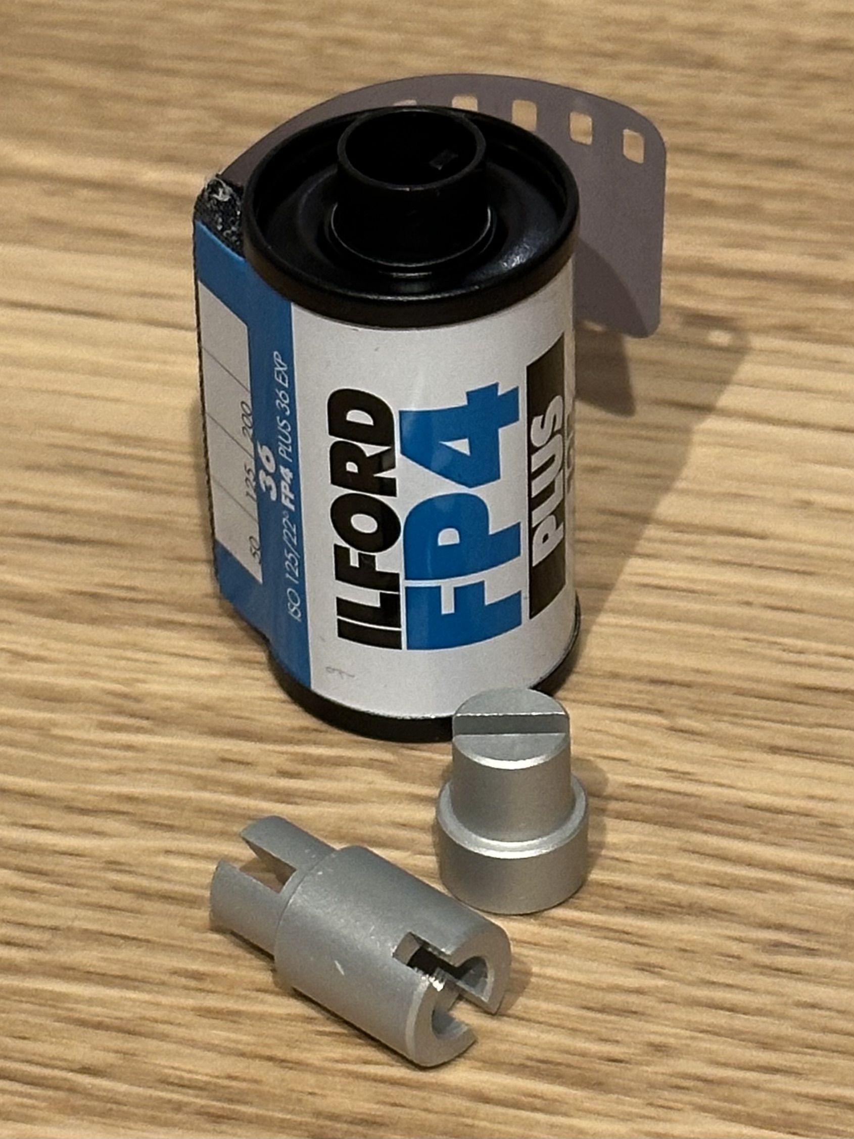 A cassette of 135 film with a set of metal 135 to 120 adapters
